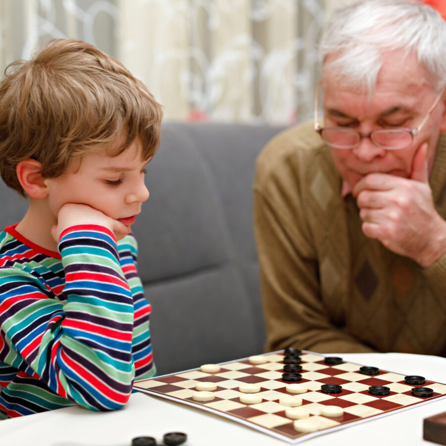 Senior man and young boy playing checkers and demonstrating therapeutic activities for the elderly