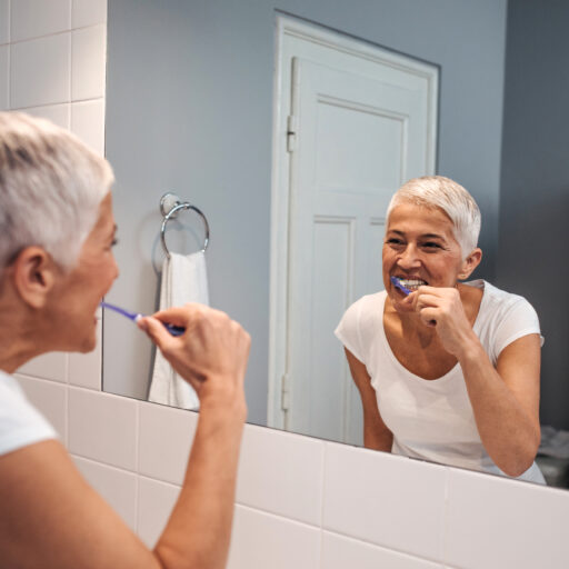 Senior woman brushing teeth | bathroom and shower safety for seniors