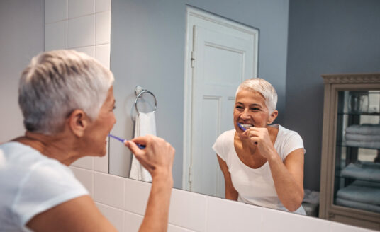 Senior woman brushing teeth | bathroom and shower safety for seniors