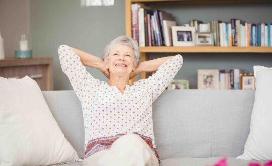 An elderly woman relaxing comfortably at home, suggesting the importance of choosing an apartment floor plan suitable for enjoyment during retirement years.