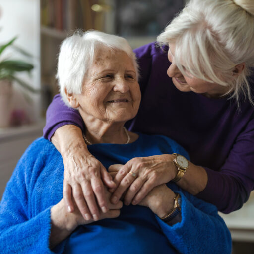 An older woman caring for an elderly parent at home