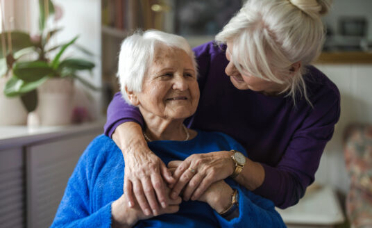 An older woman caring for an elderly parent at home