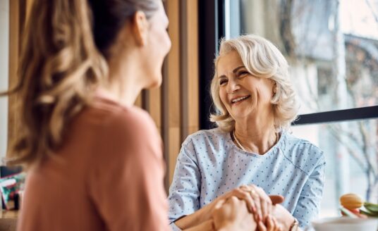 Happy senior woman enjoys in conversation with her adult daughter in cafe.