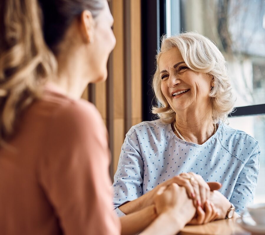 Happy senior woman enjoys in conversation with her adult daughter in cafe.