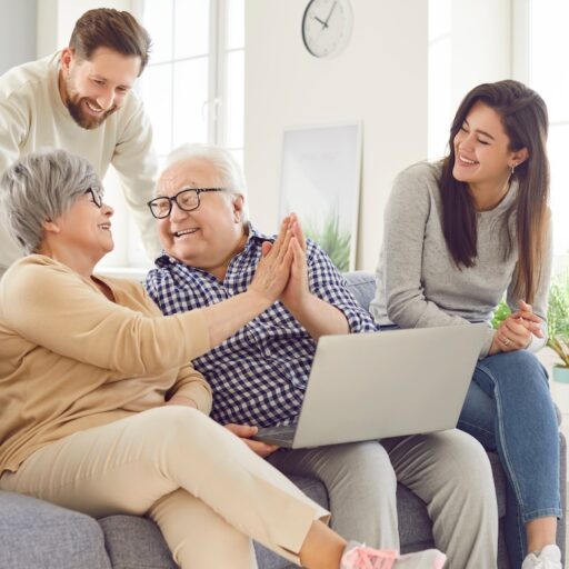 Happy family, aging old parents and adult children, two generations learn using laptop online home.