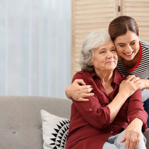 A caregiver embracing an older adult in her home.