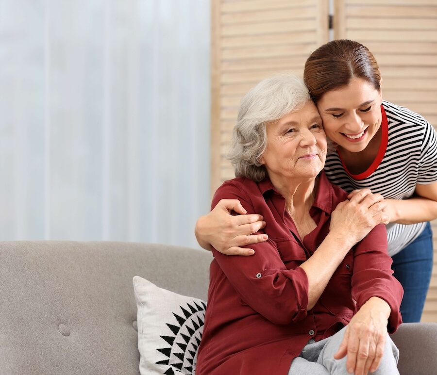 A caregiver embracing an older adult in her home.