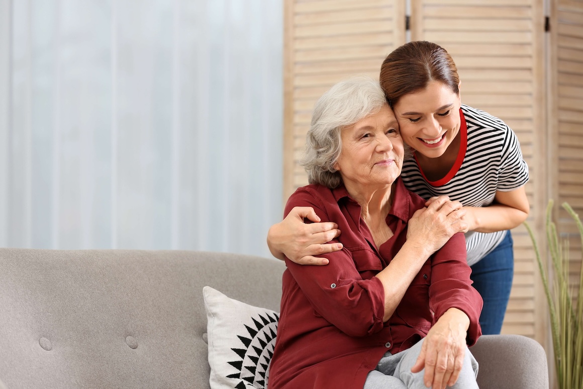 A caregiver embracing an older adult in her home.