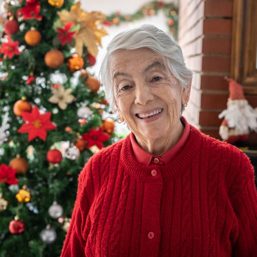 Senior woman standing in front of Christmas tree