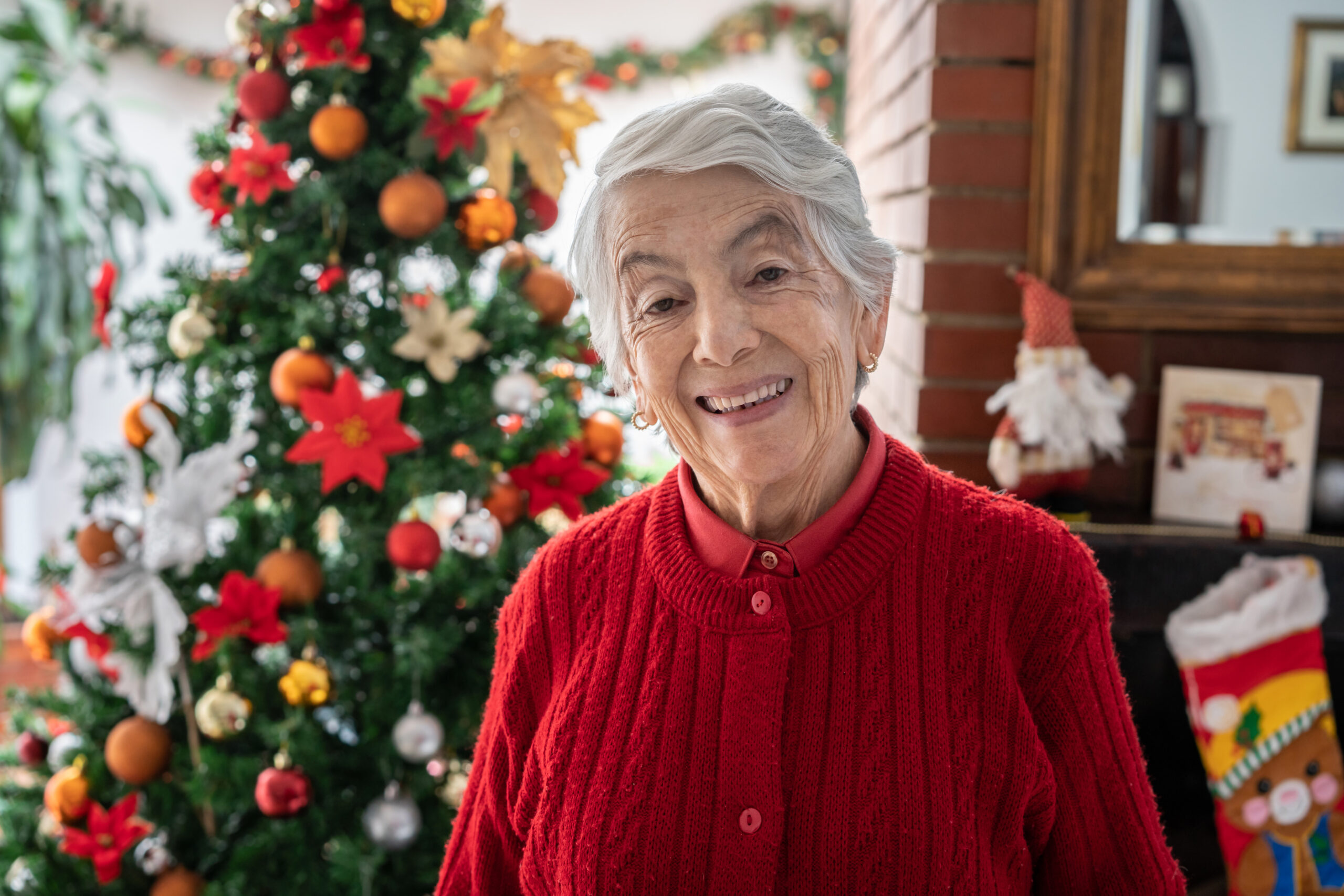 Senior woman standing in front of Christmas tree