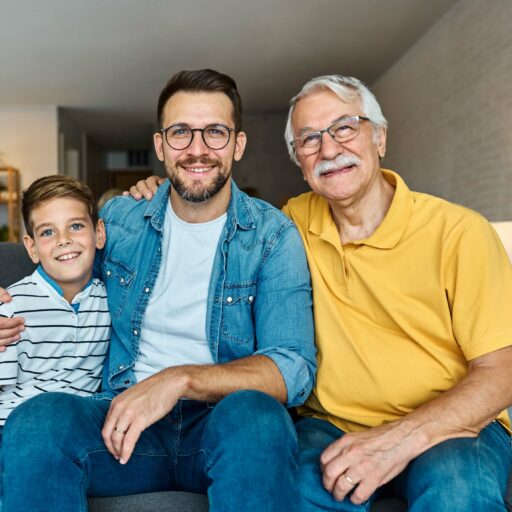 Three generational family seated on a sofa in a cozy living room.