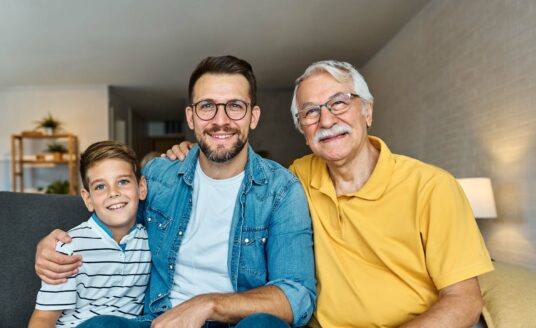 Three generational family seated on a sofa in a cozy living room.