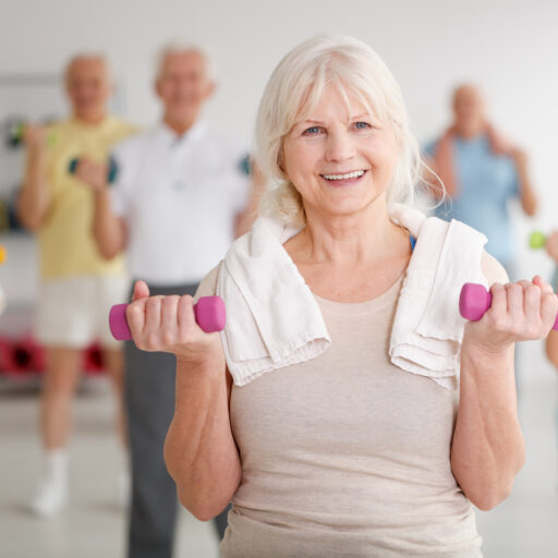 Senior woman participating in a senior exercise class with dumbbells