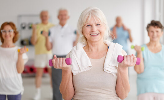 Senior woman participating in a senior exercise class with dumbbells