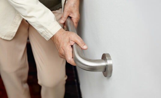 Woman using grab bars, helpful fall prevention devices