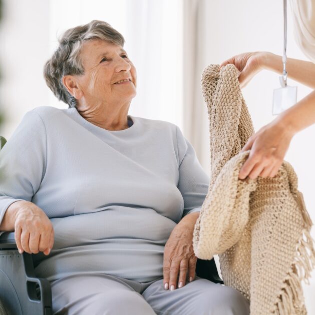 Hospice volunteer hands patient a blanket