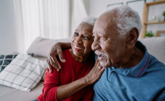Senior couple hugging on couch | Assisted Living Options for Couples