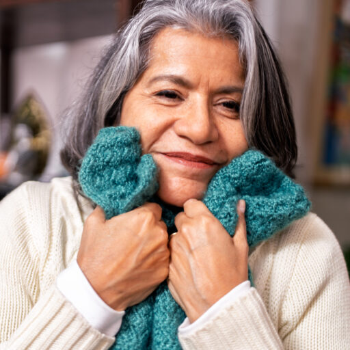 Senior woman hugging knitted blanket, one of many comfort items beneficial to dementia patients