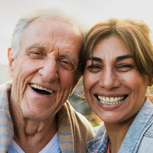 Woman smiling and embracing senior man, maintaining a positive attitude to avoid caregiver burnout.