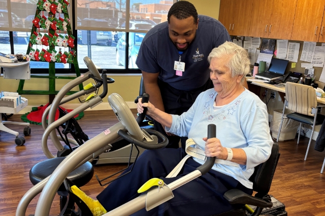 Senior on an exercise machine with trainer