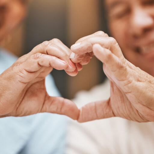 Two seniors making a heart with their hands to support senior heart health