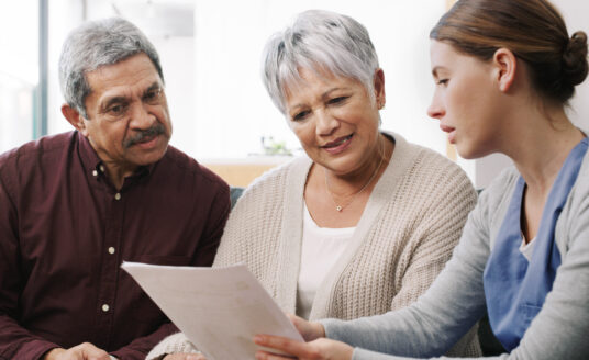 Care management professional teaching senior couple about personalized care plans
