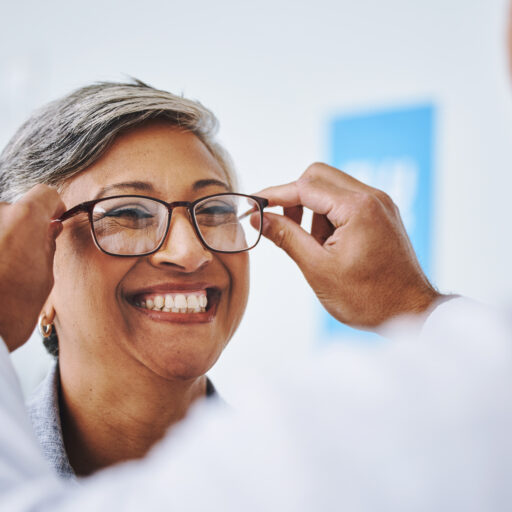Senior woman trying on glasses at senior eye care exam