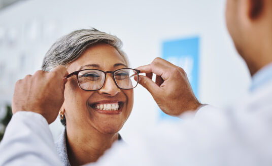 Senior woman trying on glasses at senior eye care exam