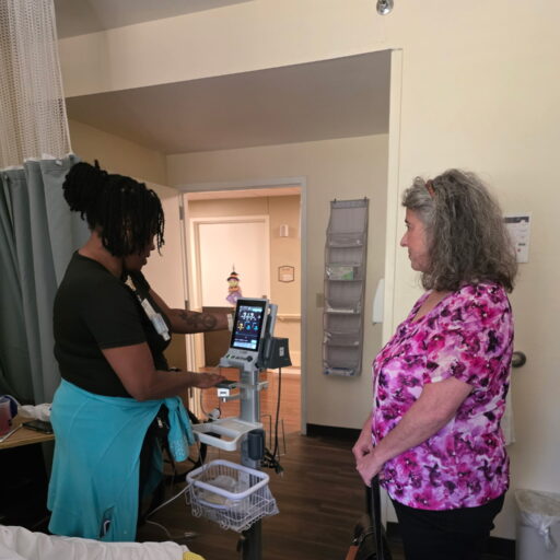 Theresa Wolff watches as staff uses new critical vital sign monitor.
