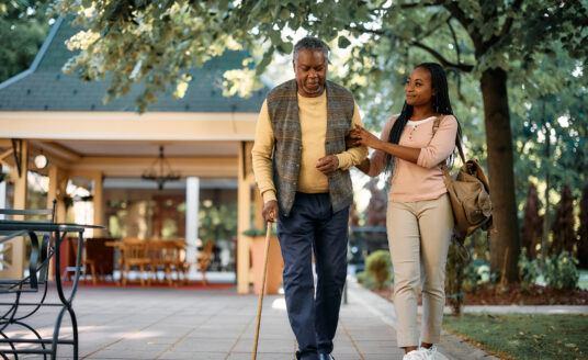 Young woman assisting senior man walking with cane, a way to show respect for the elderly